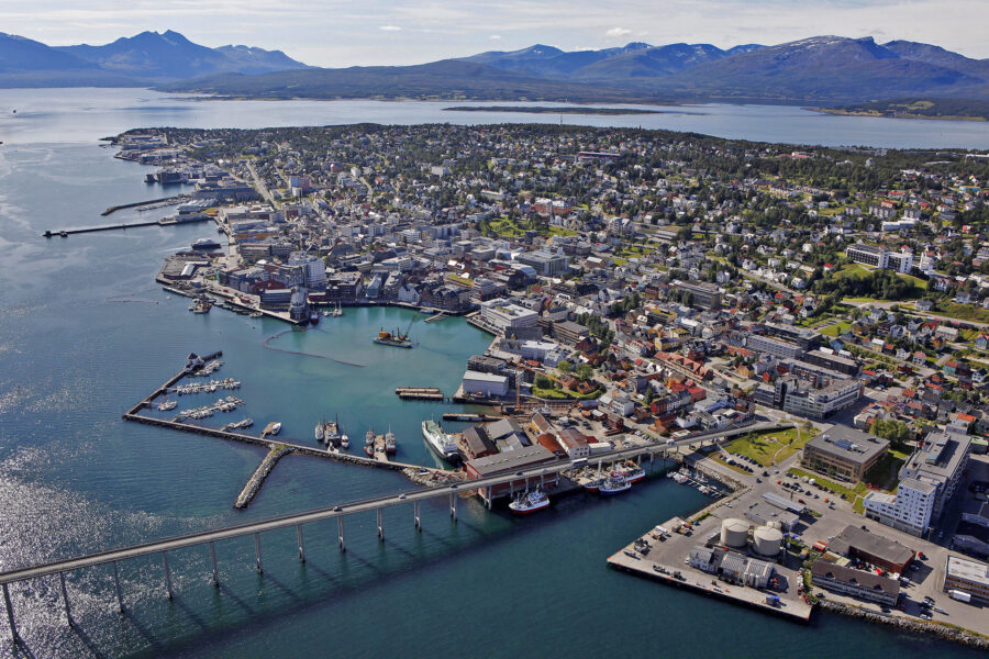 Aerial view of Tromsø Harbor with mountains, boats, and buildings in northern Norway.