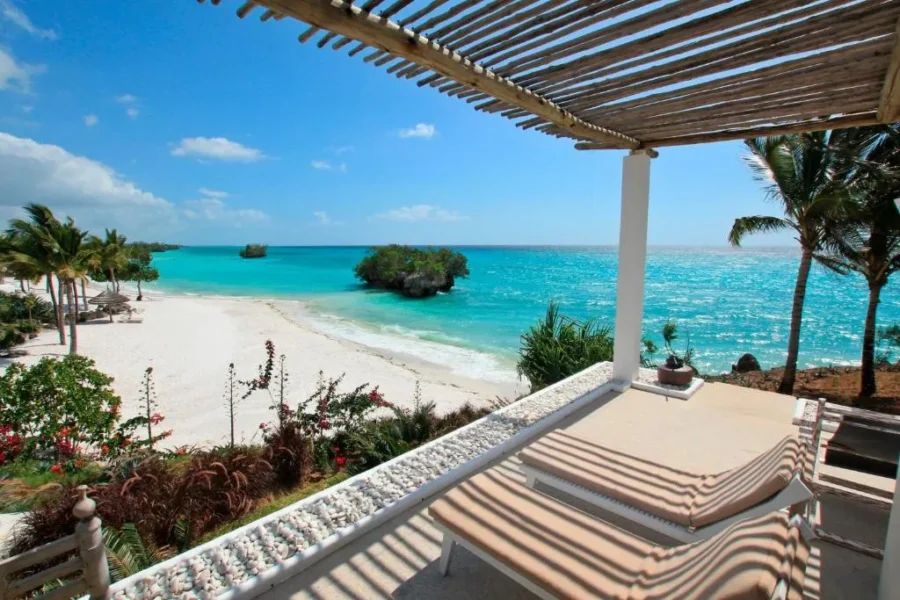 Luxury tropical oceanview terrace with lounge chairs overlooking white sand beach and turquoise sea.