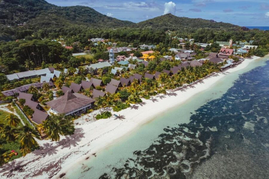 Aerial view of tropical beachfront resort town with palm trees, white sand beach and turquoise water.