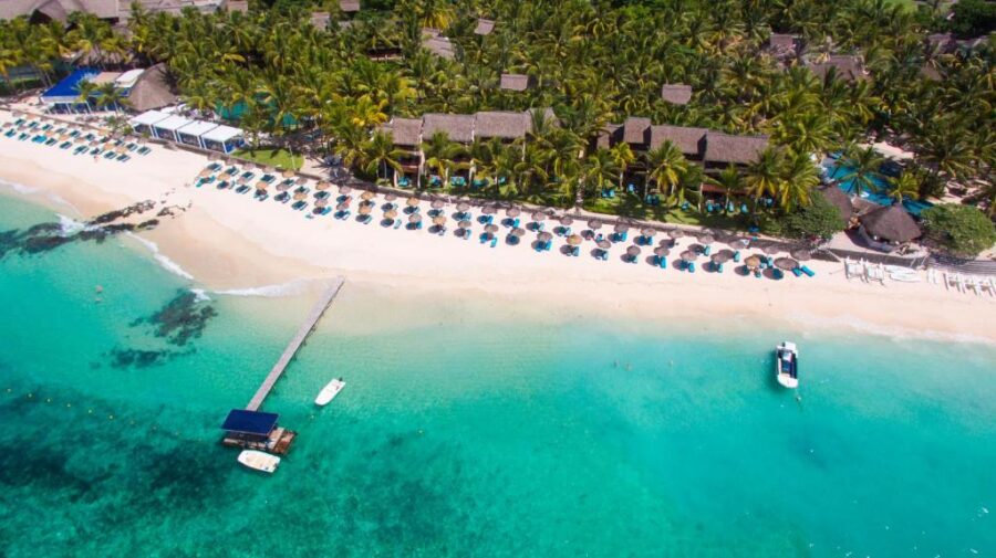 Aerial view of luxury tropical beach resort with palm trees, turquoise lagoon, pools, and white sand.