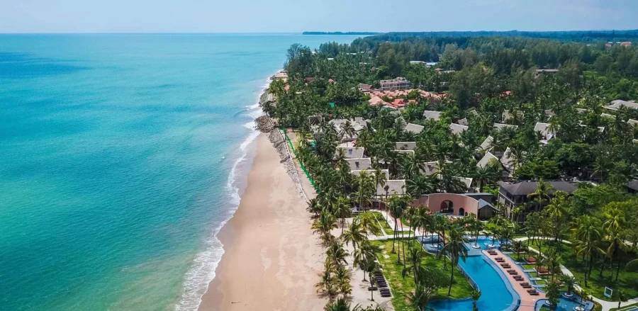 Aerial view of Bang Sak tropical beachfront resort with palm trees, golden sand and turquoise sea.