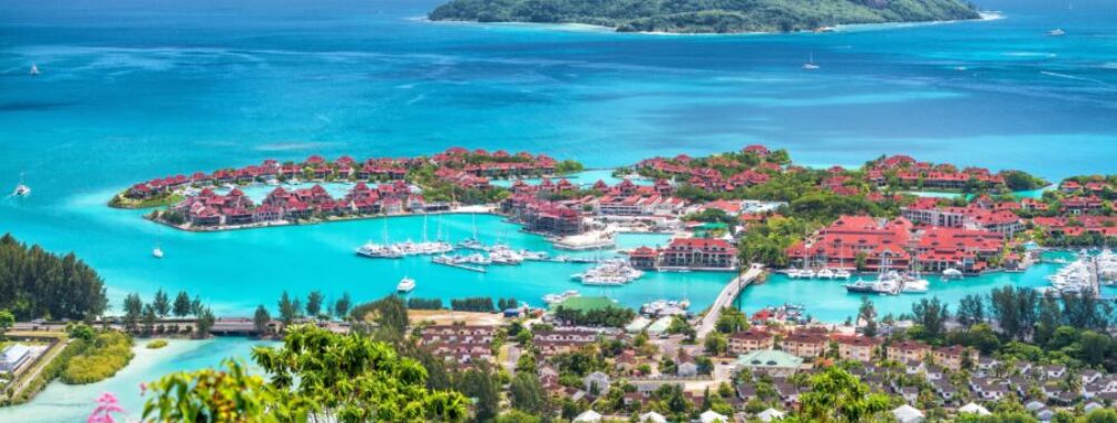 Luxury tropical marina resort with turquoise lagoon, yachts, villas, lush island and blue ocean.