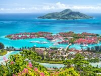 Luxury tropical marina resort with turquoise lagoon, yachts, villas, lush island and blue ocean.