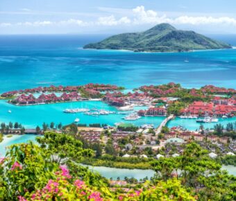 Luxury tropical marina resort with turquoise lagoon, yachts, villas, lush island and blue ocean.