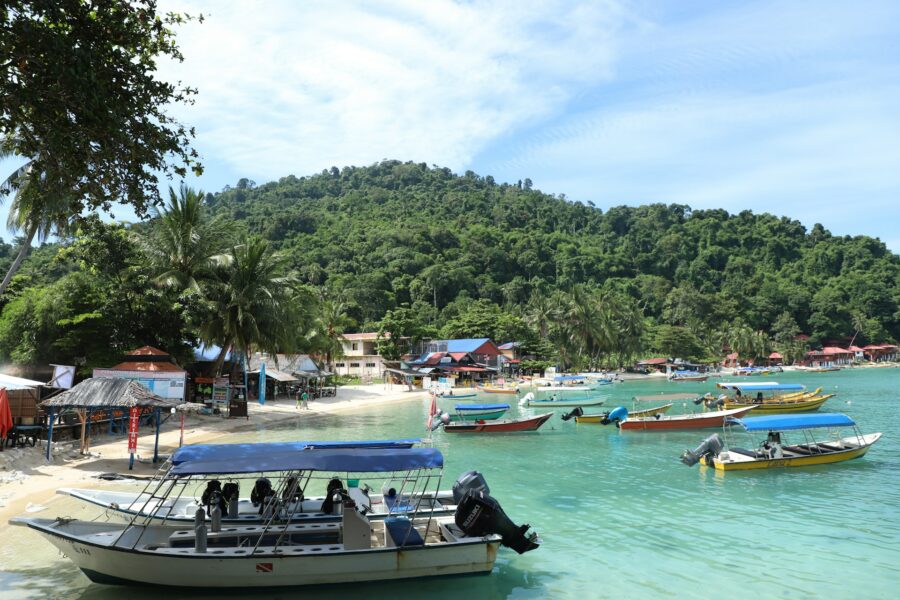 Paraggi Beach tropical bay with diving boats, clear turquoise water and palm-lined shore.