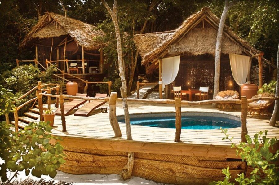 Secluded tropical eco resort with plunge pool, thatched huts, jungle deck and lounge chairs.