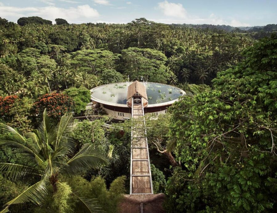 Luxury jungle resort with circular rooftop pool and elevated walkway in lush tropical Bali forest.