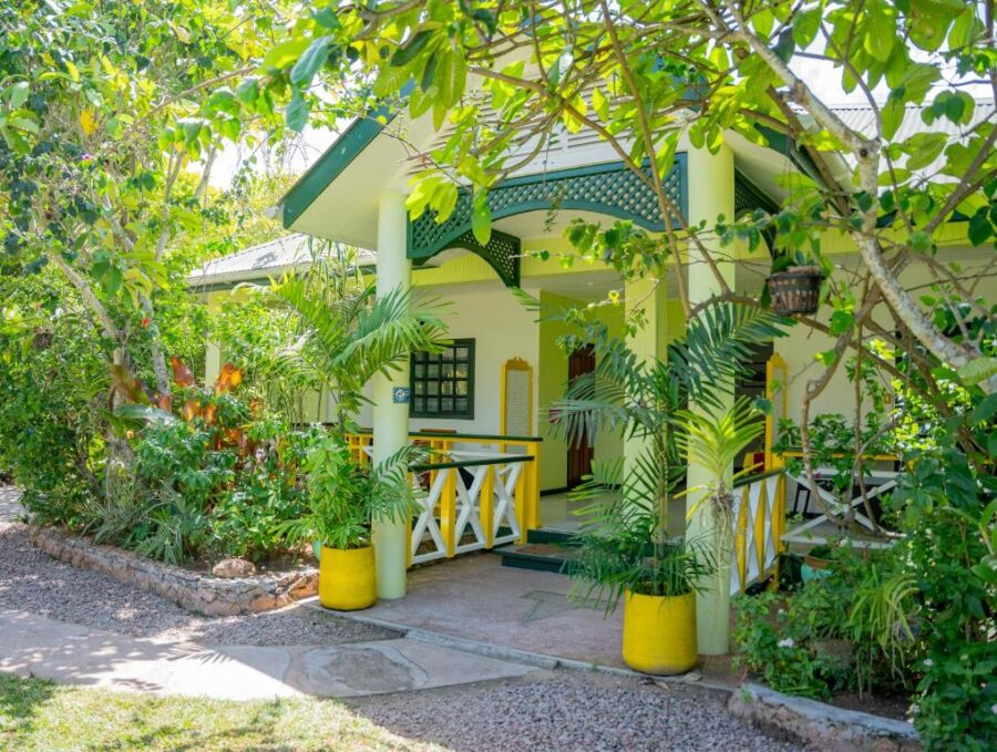 Tropical garden bungalow with colorful porch, lush greenery, and vacation guesthouse entrance.