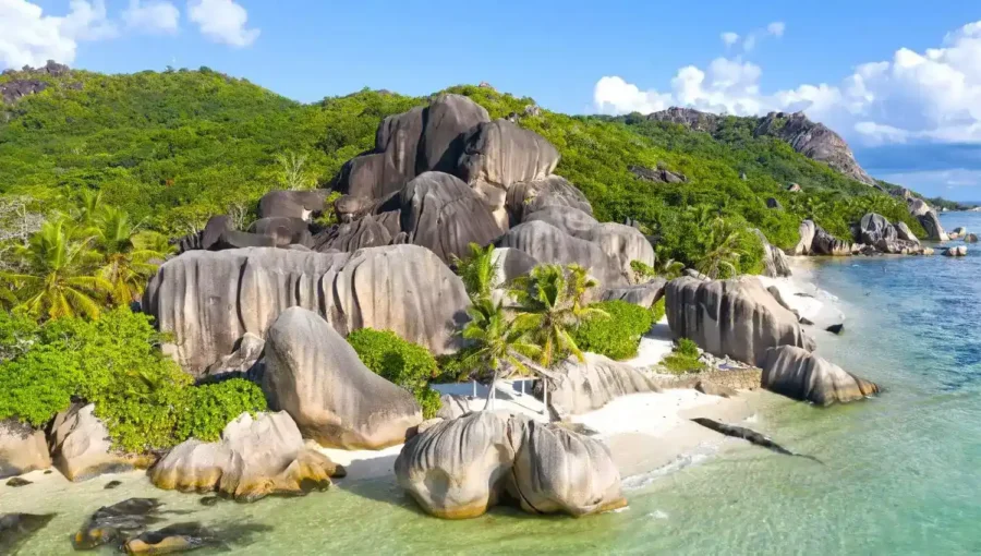 Tropical beach with turquoise water, white sand, granite boulders and lush palm trees paradise.
