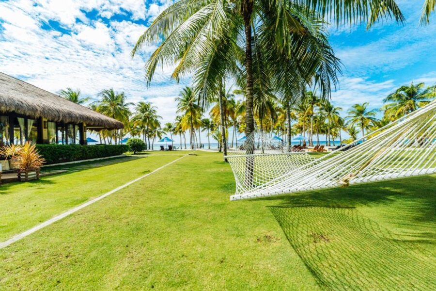 Tropical Bohol beachfront resort with hammock and swaying palm trees.