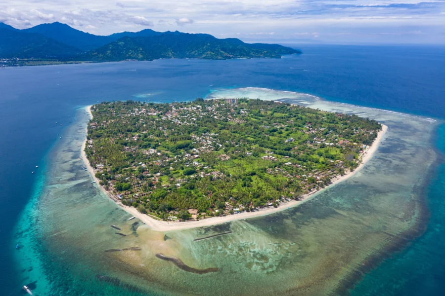 Aerial view of tropical Gili Air island with turquoise water, coral reef, beach and palm trees.