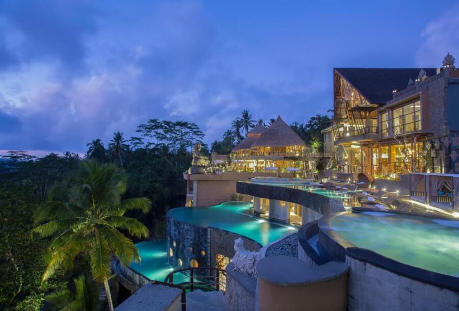 Luxury tropical hillside infinity pool resort at dusk overlooking jungle valley in Bali.