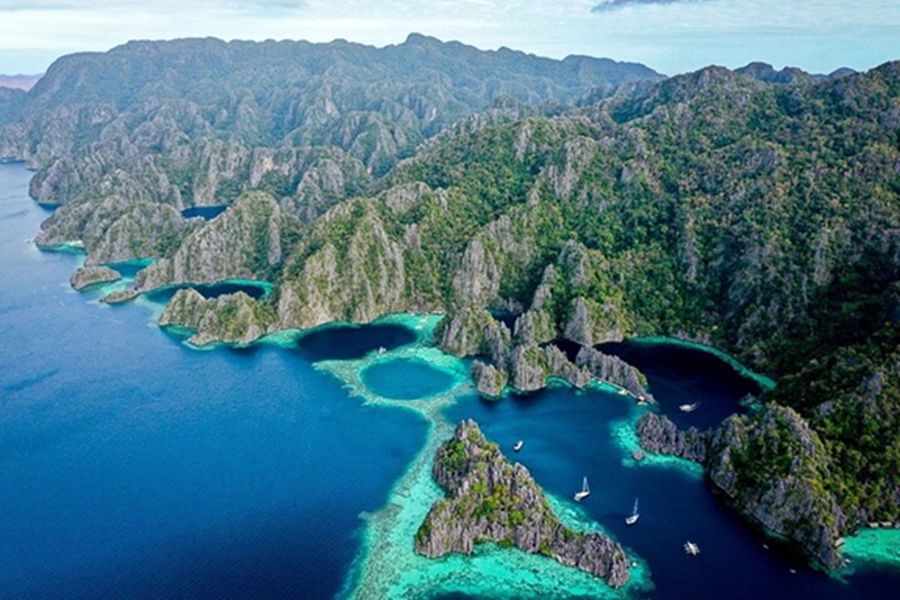 Aerial view of tropical limestone islands with turquoise lagoons and steep cliffs.