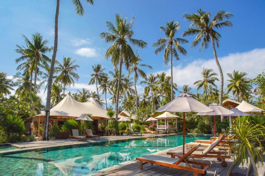 Luxury tropical resort pool with palm trees, cabanas, sun loungers and umbrellas in paradise.