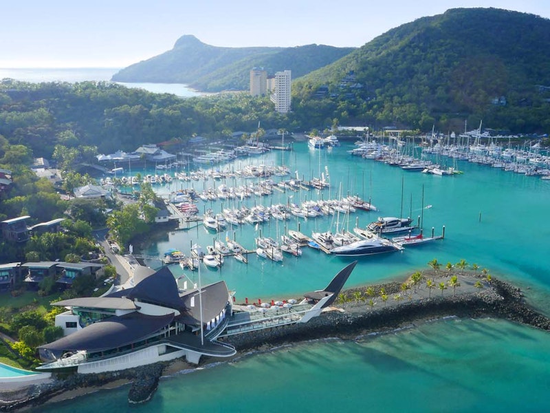 Luxury tropical marina on Hamilton Island with yachts, modern waterfront architecture, and lush green hills.