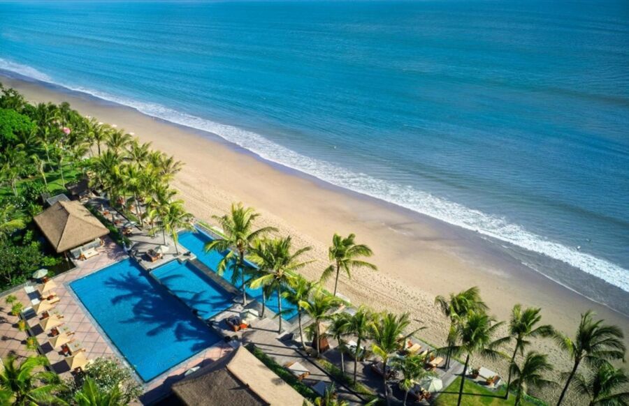 Stunning aerial view of serene Legian beachfront resort with pool and golden sandy beach.