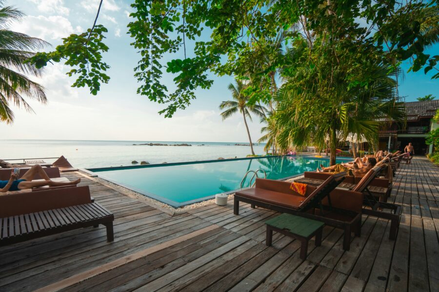 Tropical poolside retreat with loungers, palm trees, serene water, and horizon view.