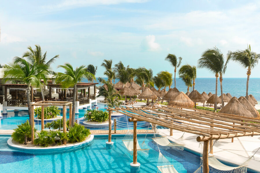 Tropical resort with pools, palm trees, cabanas, ocean view, luxury, relaxation, vacation paradise.