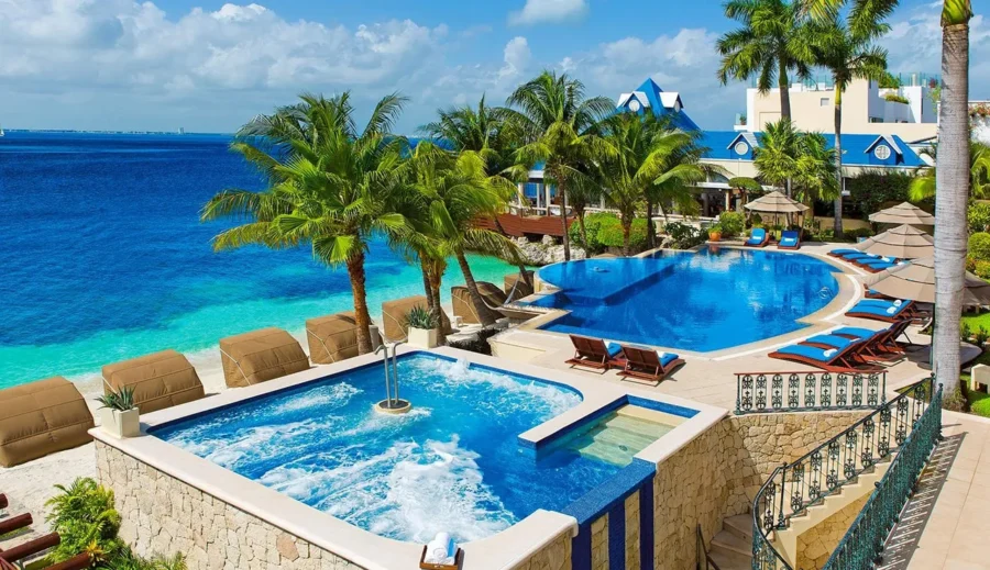Luxurious tropical resort pool with ocean view, palm trees, and comfortable lounge areas.