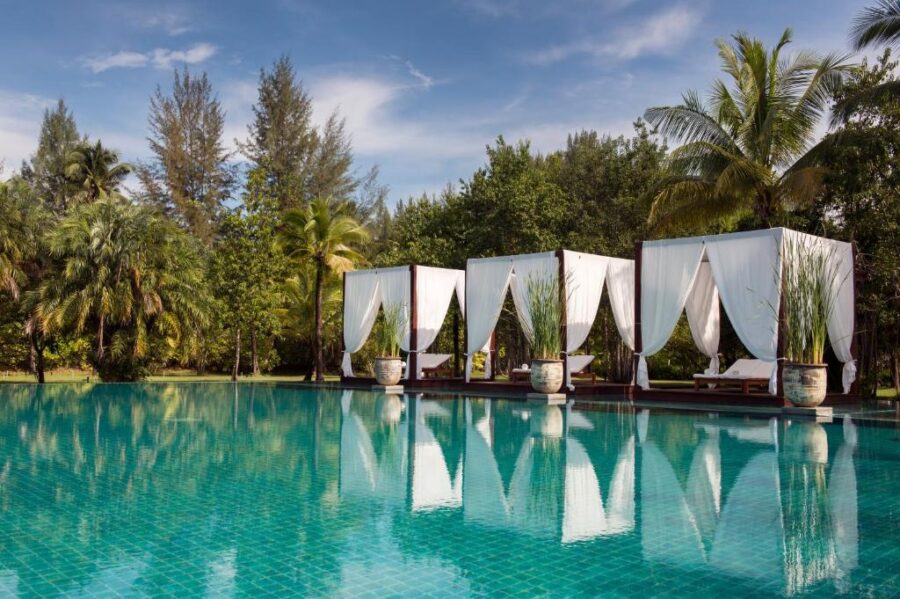 Luxury tropical resort swimming pool with cabanas, palm trees, and relaxing sunny vacation atmosphere.