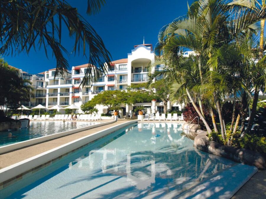 Luxury Gold Coast resort with tropical palm trees, lagoon pool, sun loungers, and beachfront hotel suites.