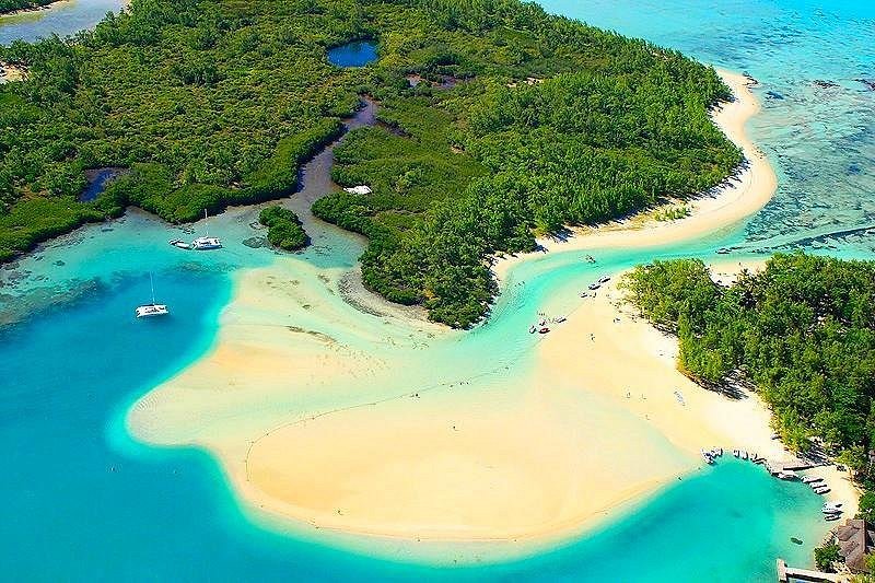 Aerial view of Île aux Cerfs sandbar, tropical lagoon, turquoise water, boats, and lush island.