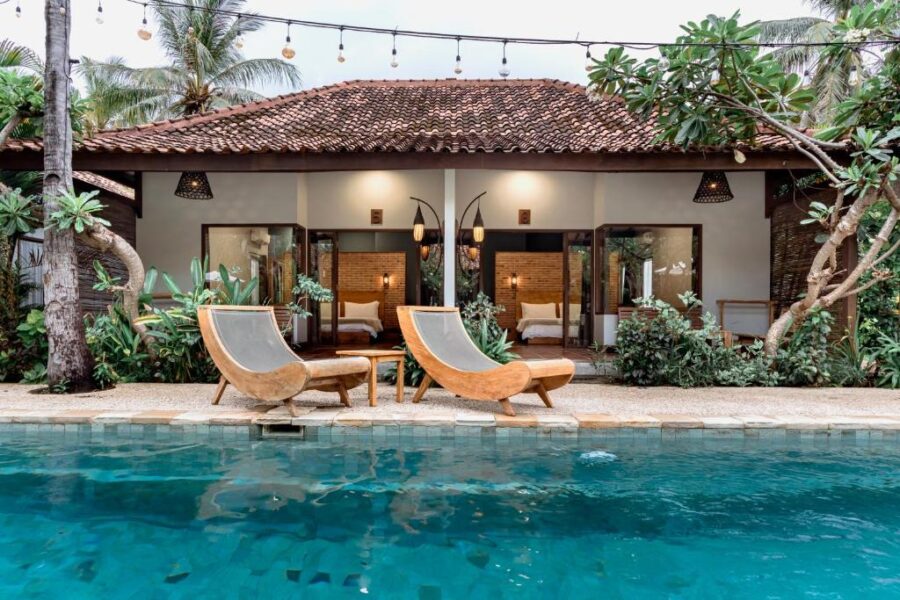 Luxury tropical villa with private pool, sun loungers, lush garden, and open-air bedroom retreat.
