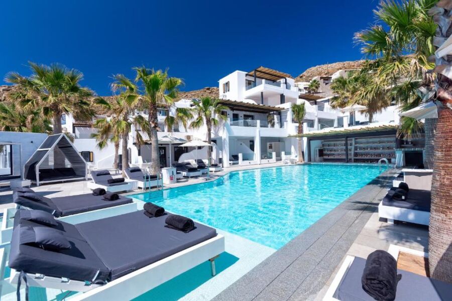 The pool area at Tropicana Hotel features lounge chairs and palm trees, creating a tropical oasis in Mykonos.
