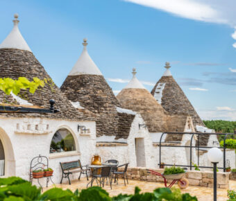 Scenic view of trulli in the Itria Valley with a clear sky, highlighting the traditional structures of Alberobello, Puglia.