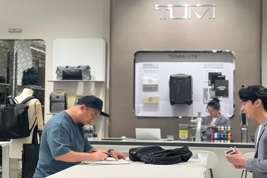 TUMI store interior: engaged customer interaction, showcasing luxury luggage and attentive service.