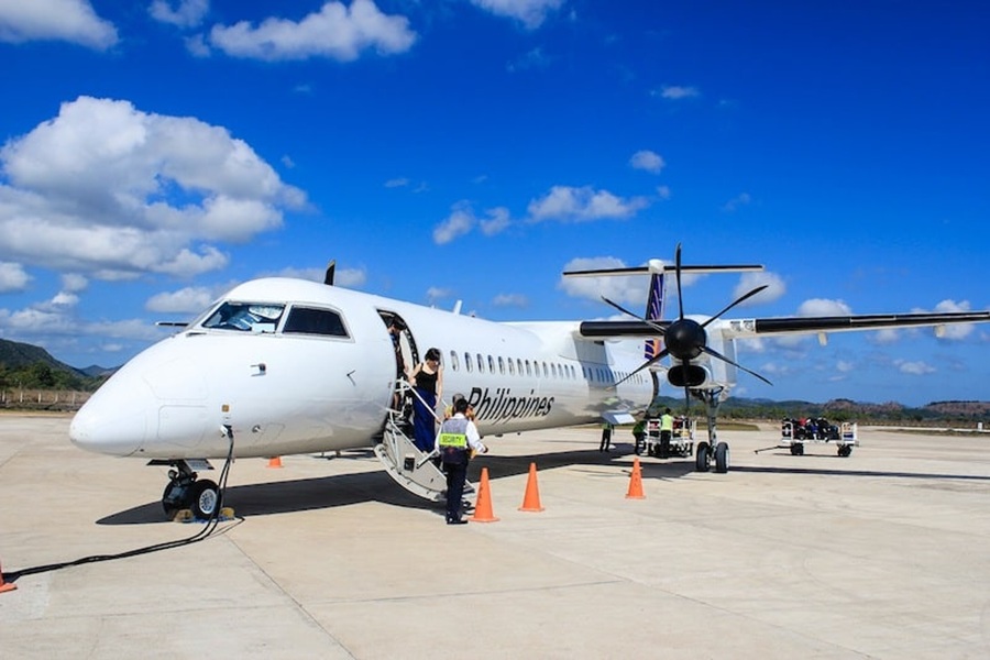 Philippines turboprop airplane boarding at Busuanga Airport ramp, passengers and ground crew.