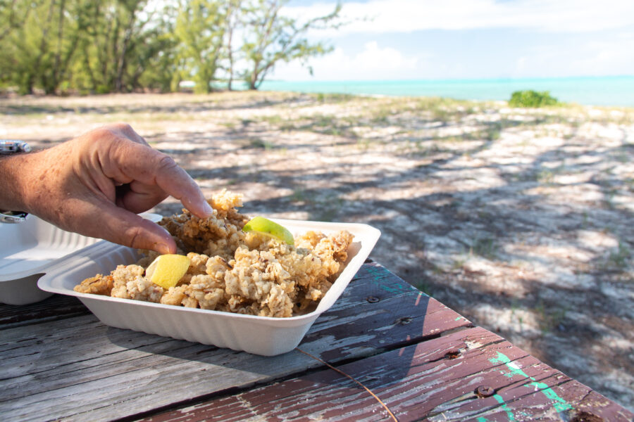 Man eating broken conch, a local dish, on Bambarra Beach in Middle Caicos, Turks and Caicos.