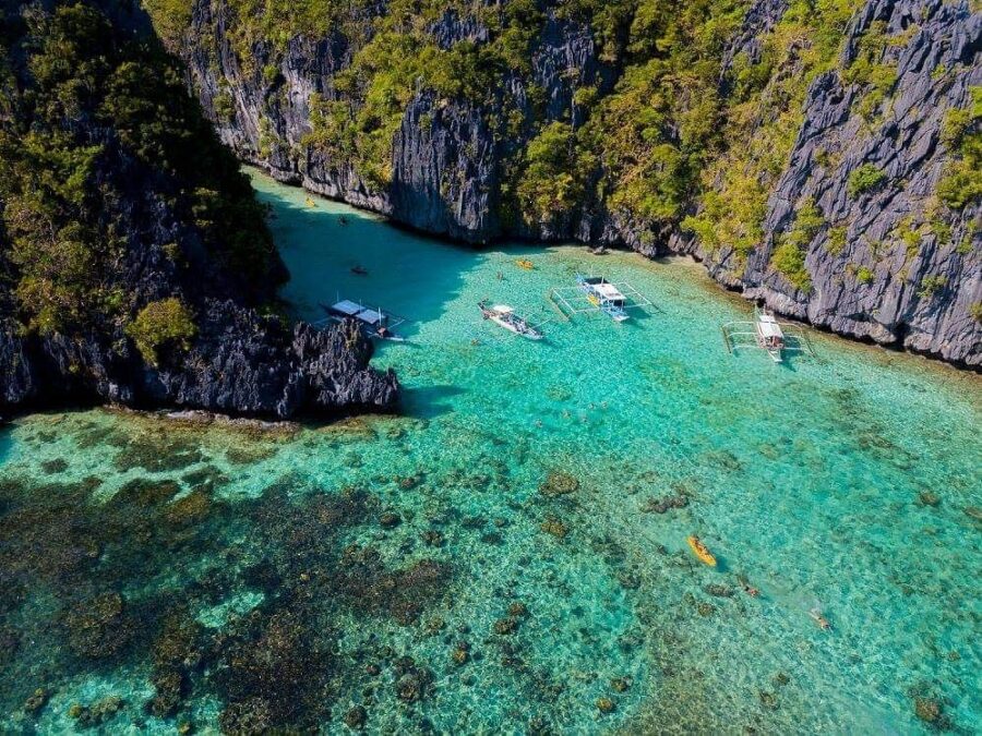 El Nido Big Lagoon: turquoise lagoon cradled by limestone cliffs with anchored outrigger boats.