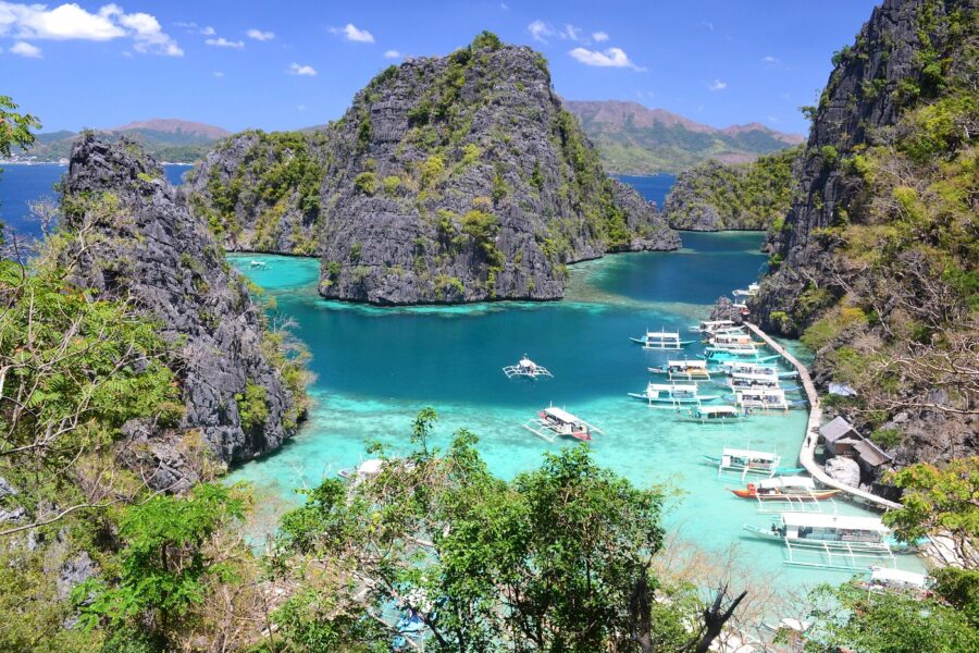 Kayangan Lake turquoise lagoon framed by limestone karst cliffs and outrigger boats.