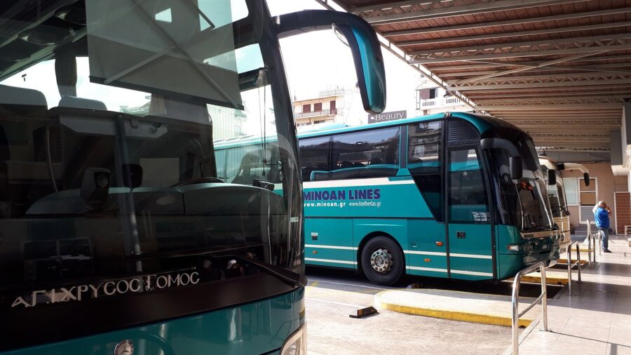 Modern turquoise coaches at a bustling terminal under clear skies, showcasing vibrant transport design.