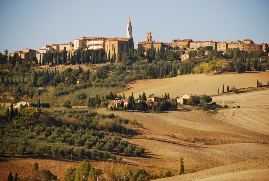 Charming Tuscan hilltop village with cypress trees, olive groves, and historical architecture.