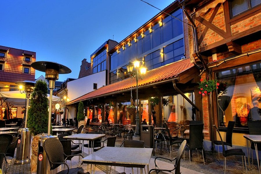 Outdoor dining area at twilight with cozy lighting and mix of traditional and modern architecture.