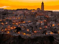 Panoramic view of historic town at twilight with stunning architecture and vibrant sunset sky.