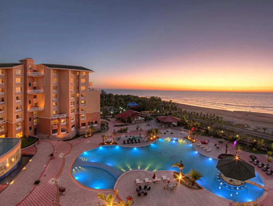 Coastal resort at sunset with pool, palm trees, and ocean views in Coxs Bazar.