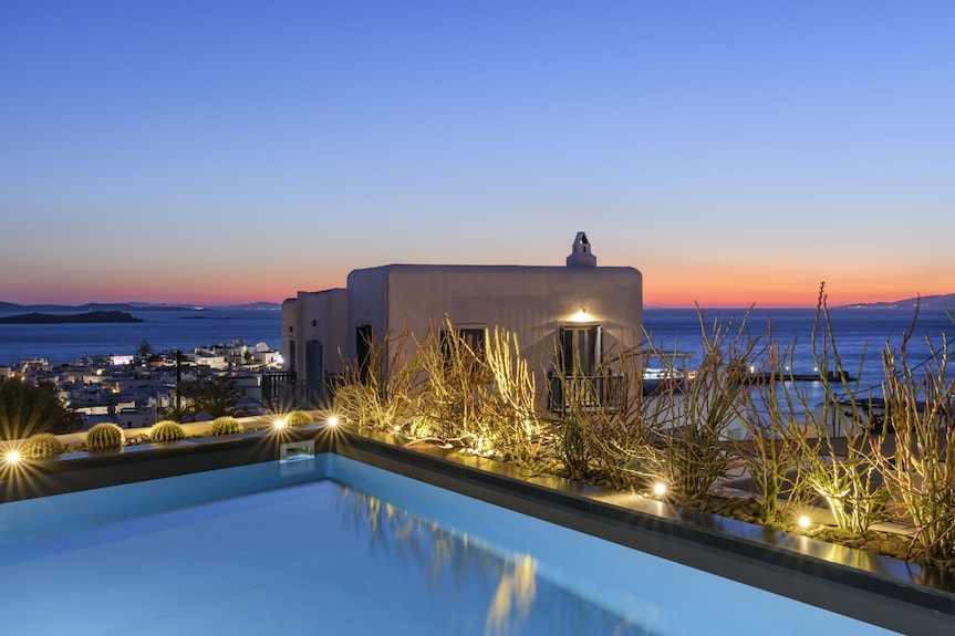 Rooftop pool with Mediterranean architecture and sea view at sunset in Mykonos.