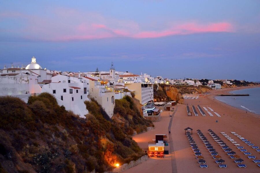 Serene Mediterranean Praia da Luz beach at dusk, featuring whitewashed buildings and inviting sandy shores.