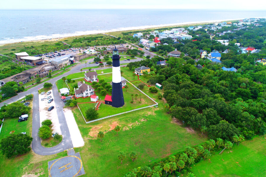 The Tybee Island Lighthouse, a historic landmark in Georgia, features distinctive black and white stripes against a sunny backdrop