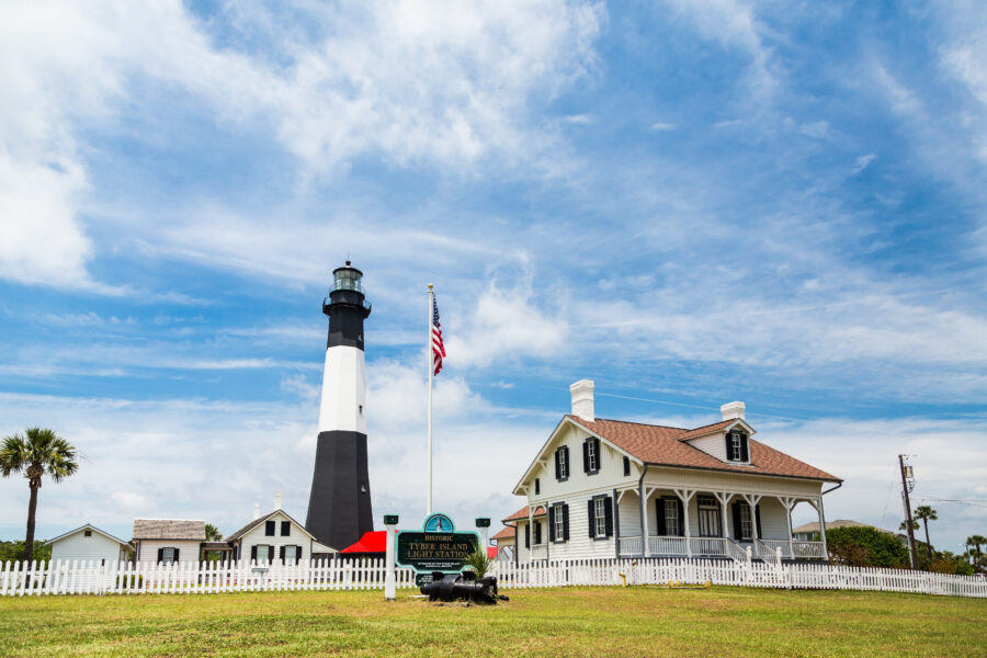 Tybee Island Lighthouse stands tall beside the historic Keepers House, showcasing coastal architecture and maritime heritage