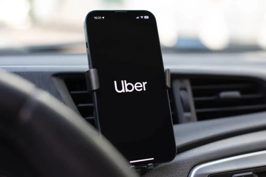 Uber app on smartphone mounted to car vent for driver navigation in Rhodes.