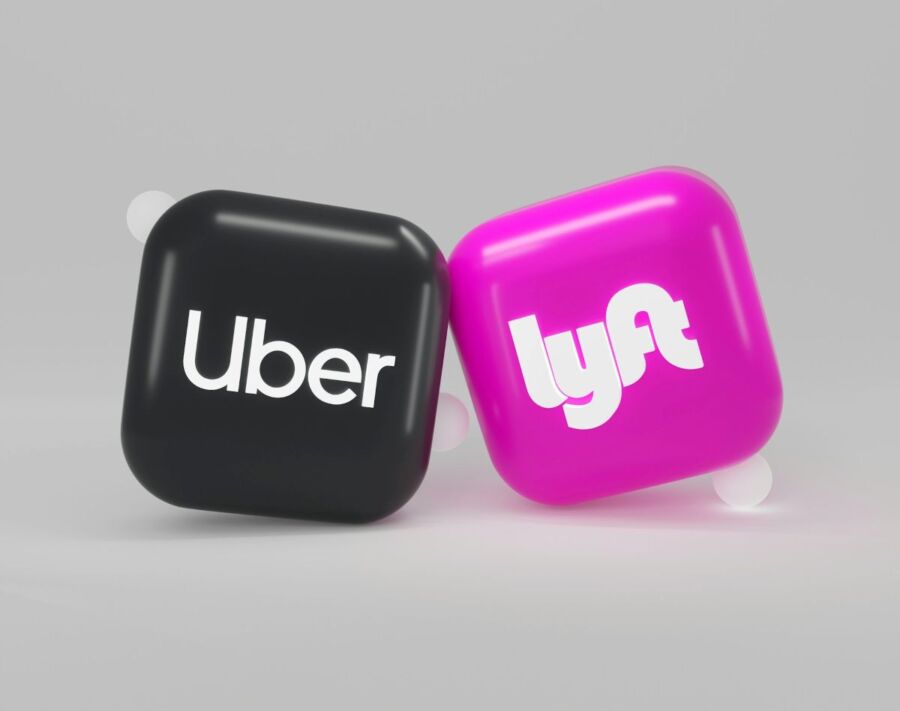 Uber and Lyft 3D logos on black and pink cubes symbolize ride-sharing rivalry.