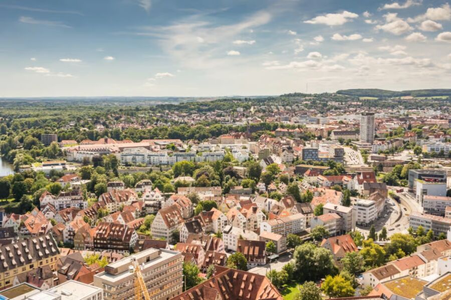 Panoramic view of Ulm, Bavaria, showcasing the city's skyline and historic architecture against a clear blue sky.