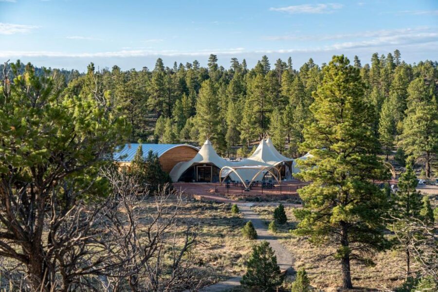 The lodge, nestled among trees, includes a spacious tent, located at Under Canvas Bryce Canyon.