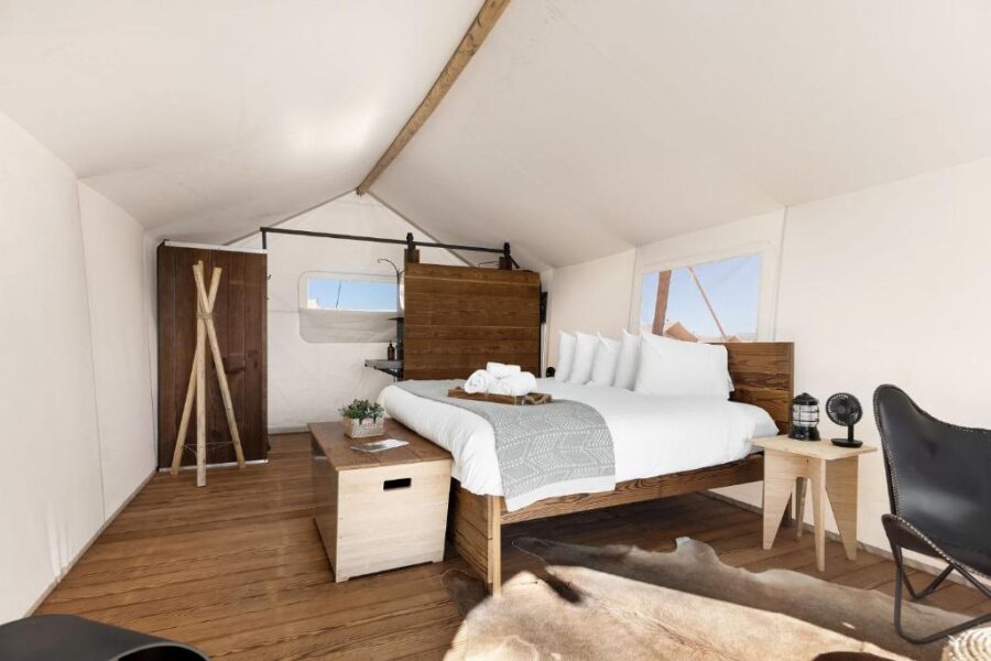 Cozy bedroom featuring a bed, desk, and a stylish cowhide rug at Under Canvas Lake Powell-Grand Staircase.