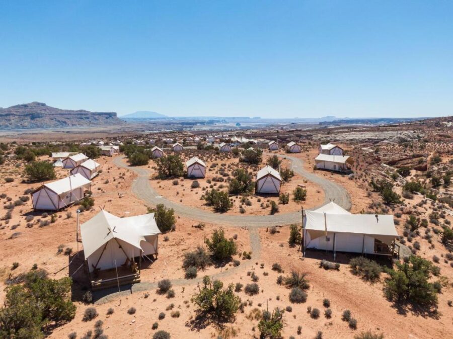 Desert campground with multiple tents set up, surrounded by stunning views at Under Canvas Lake Powell-Grand Staircase Panorama.