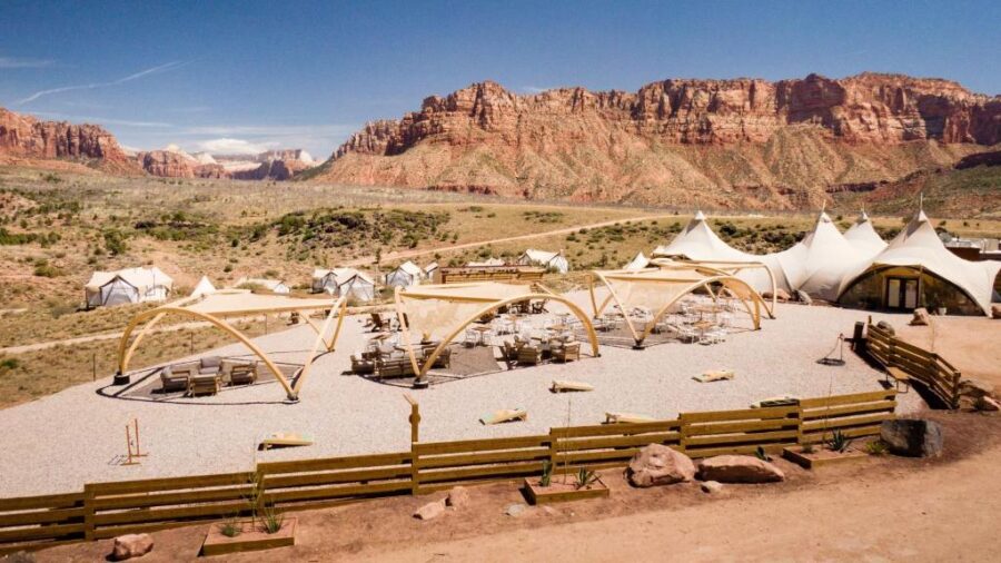 Tent set against a desert landscape and mountains, highlighting the Under Canvas Zion camping location.